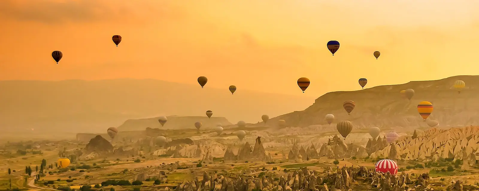 Hot-air balloons over fairy chimneys at sunrise, Cappadocia